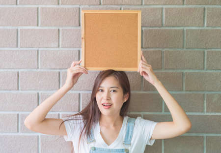 Asian woman with cork board in hand with excited faceの写真素材