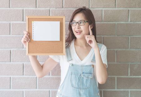Asian woman with cork board in hand with have an idea faceの写真素材