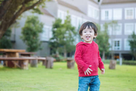 Closeup happy asian kid stand on grass floor in the garden background with fun motionの写真素材