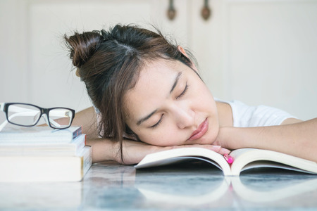 Woman sleeping after she tired for reading with a book on marble table in front of houseの写真素材