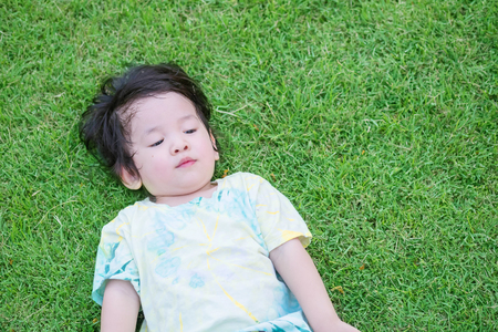 Closeup asian kid lied on grass floor and look something in the garden background with copy spaceの写真素材