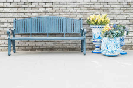 Closeup wood chair with fake flowers in vase on blurred brick wall and floor textured background with copy spaceの写真素材