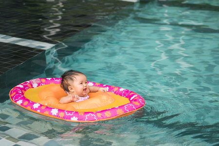 Closeup little girl sit in a boat for children with smile face in the swimming pool background with copy spaceの写真素材