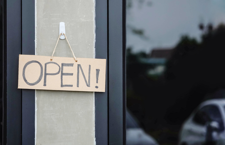 Closeup brown hard paper signboard with open massage in front of coffee shop backgroundの写真素材