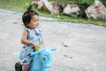 Closeup a little girl ride a bicycle toy for kid with happy face on cement floor in the park textured background with copy spaceの写真素材