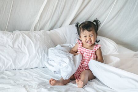 Closeup a little girl sit on bed with smile face in the morningの写真素材