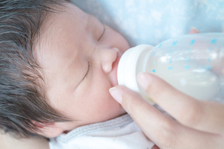 The child is sucking mother's milk from the bottle