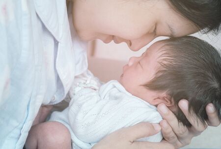 Closeup a baby sleeping comfortably in the mother's armsの写真素材