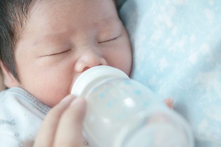 Closeup a baby girl is sucking mother's milk from the bottle