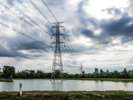 The sky is overcast, it will rain, high voltage pole in the middle of the field. and reservoirsの写真素材