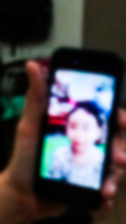 A woman talk face to face with his son at night by phone. Blurred abstract form.の写真素材