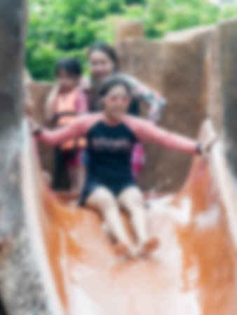 People swimming in the resort pool beside the batting with water slides, a play. Abstract blur.