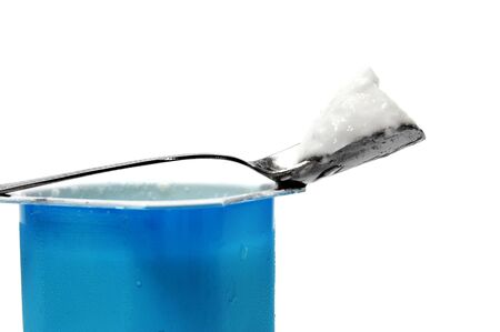 a plain yogurt with some of it on a spoon on a white backgroundの写真素材