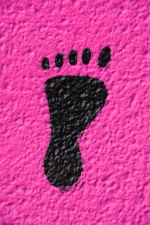a black footprint painted on a pink wallの写真素材