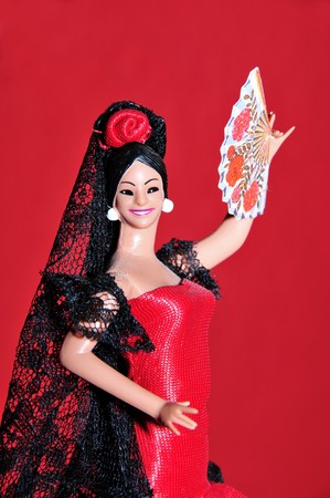 a typical spanish doll dressed as a flamenca isolated on a RED backgroundの写真素材