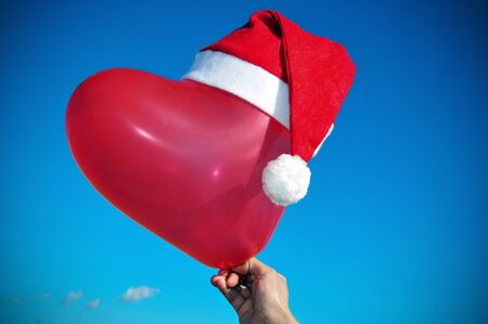 a santa hat in a heart-shipped balloon, symbolizing "I love Christmas"の写真素材