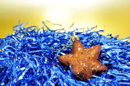 a golden christmas star and blue tinsel on a golden background の写真素材