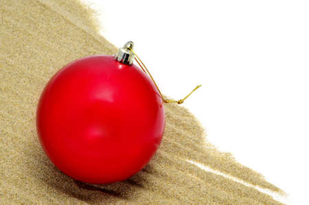 a red christmas ball on the sandの写真素材