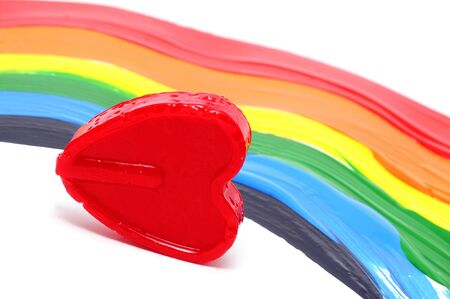 a heart-shapped lollipop on a rainbow backgroundの写真素材