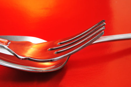 closeup of a fork and a spoon on a red backgroundの写真素材