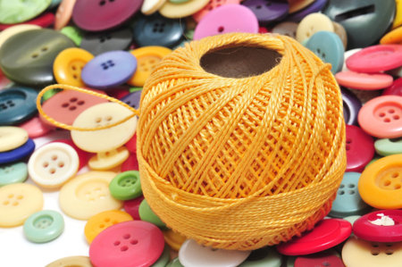 a spool of thread and buttons of many colors on a white background