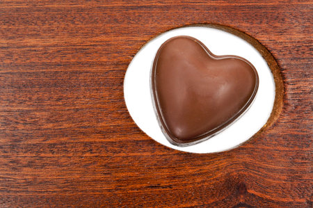 a heart shaped chocolate on a hole in a wooden blackboard