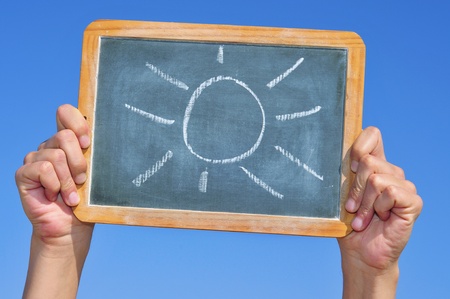 someone holding a blackboard with a sun drawn in itの写真素材