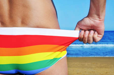 someone adjusting his rainbow swimsuit on the beachの写真素材