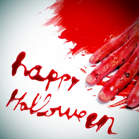 sentence Happy Halloween written with blood and a scary and bloody hand in a pool of bloodの写真素材