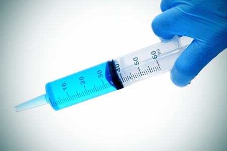 someone wearing medical gloves holding a syringeの写真素材