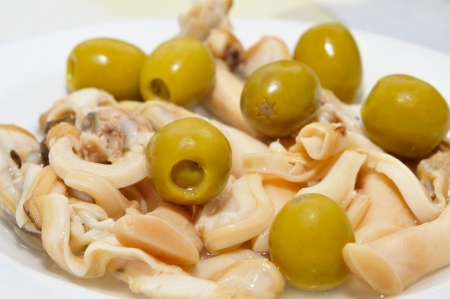a plate with navajas, spanish jackknife clams, served as appetizer with vinegar and paprika, and some olivesの写真素材