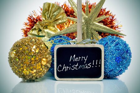some christmas ornaments and the sentence merry crhistmas written in a blackboard label, with a retro effectの写真素材