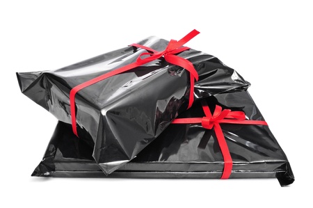 a pile of gifts wrapped with black plastic and tied with red ribbons on a white background の写真素材