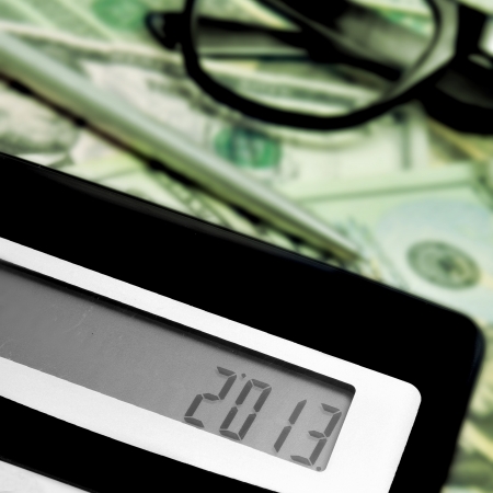 number 2013, as the new year, on the display of a calculator, with some dollar bills in the backgroundの写真素材