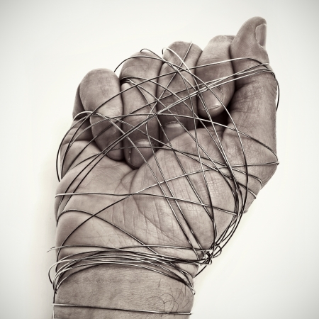 man hand tied with wire, as a symbol of oppression or repression, on a white backgroundの写真素材