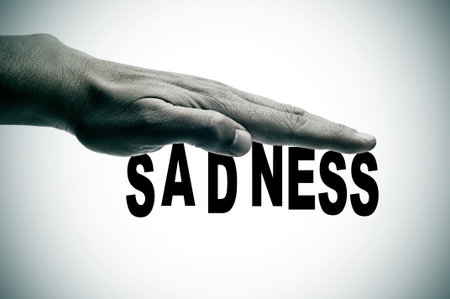 a man hand and the sentence sadness written in black