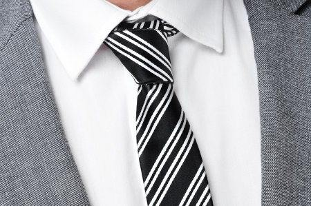detail of a man wearing a gray jacket suit, white shirt and black and white striped tieの写真素材