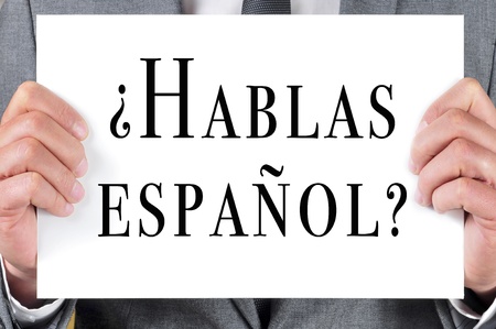 a man wearing a suit holding a signboard with the sentence hablas espanol  do you speak spanish  written in spanish on itの写真素材