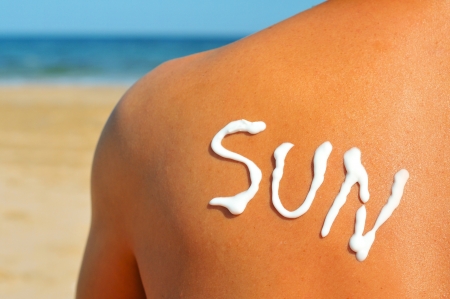 the word sun written with sunblock on the back of a man who is sunbathing on the beachの写真素材