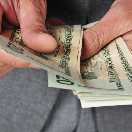 a man wearing a suit counting dollar billsの写真素材