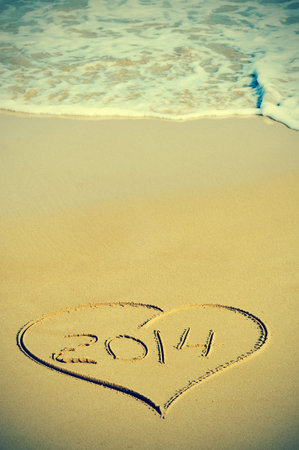 picture of a heart drawn on the sand of a beach with the number 2014, as the new year, written...