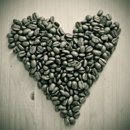a pile of roasted coffee beans forming a heart, on a wooden table , in black and whiteの写真素材