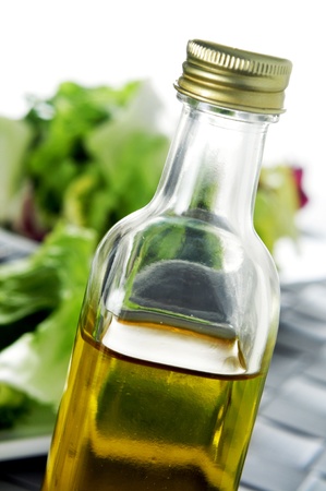 closeup of a bottle of spanish olive oil on a set table, with a plate with lettuce in the backgroundの写真素材