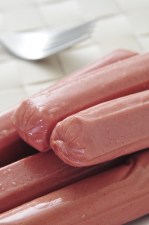 closeup of some raw hot dogs ready to be grilled on a tableの写真素材
