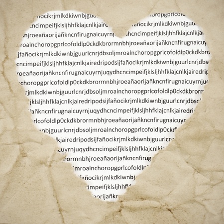 a heart-shaped hole on an old paper with a printed paper with letters in the background, with a retro effectの写真素材