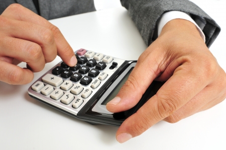 a businessman sitting in a desk using a calculatorの写真素材