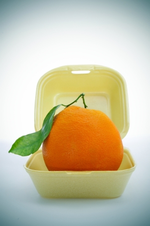 an appetizing orange in a foam food container, as a fast food, this is fast fruit, or symbolizing the replacement of fast food for healthy foodの写真素材