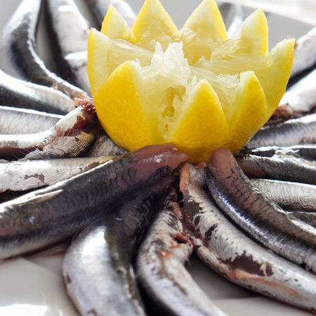 a plate with some raw spanish boquerones, anchovies typical in Spain, ready to be cooked