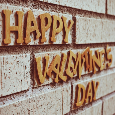 wooden letters forming the sentence happy valentines day on a brick wall, with a retro effectの写真素材