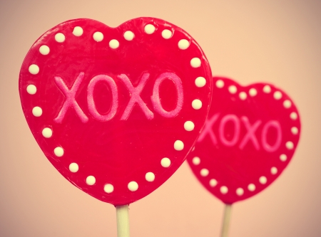 picture of some heart-shaped lollipops with the text XOXO, hugs and kisses, written in them, with a retro effectの写真素材